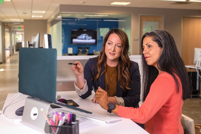 How We Work – Project Management Two women at a desk working together on a computer.