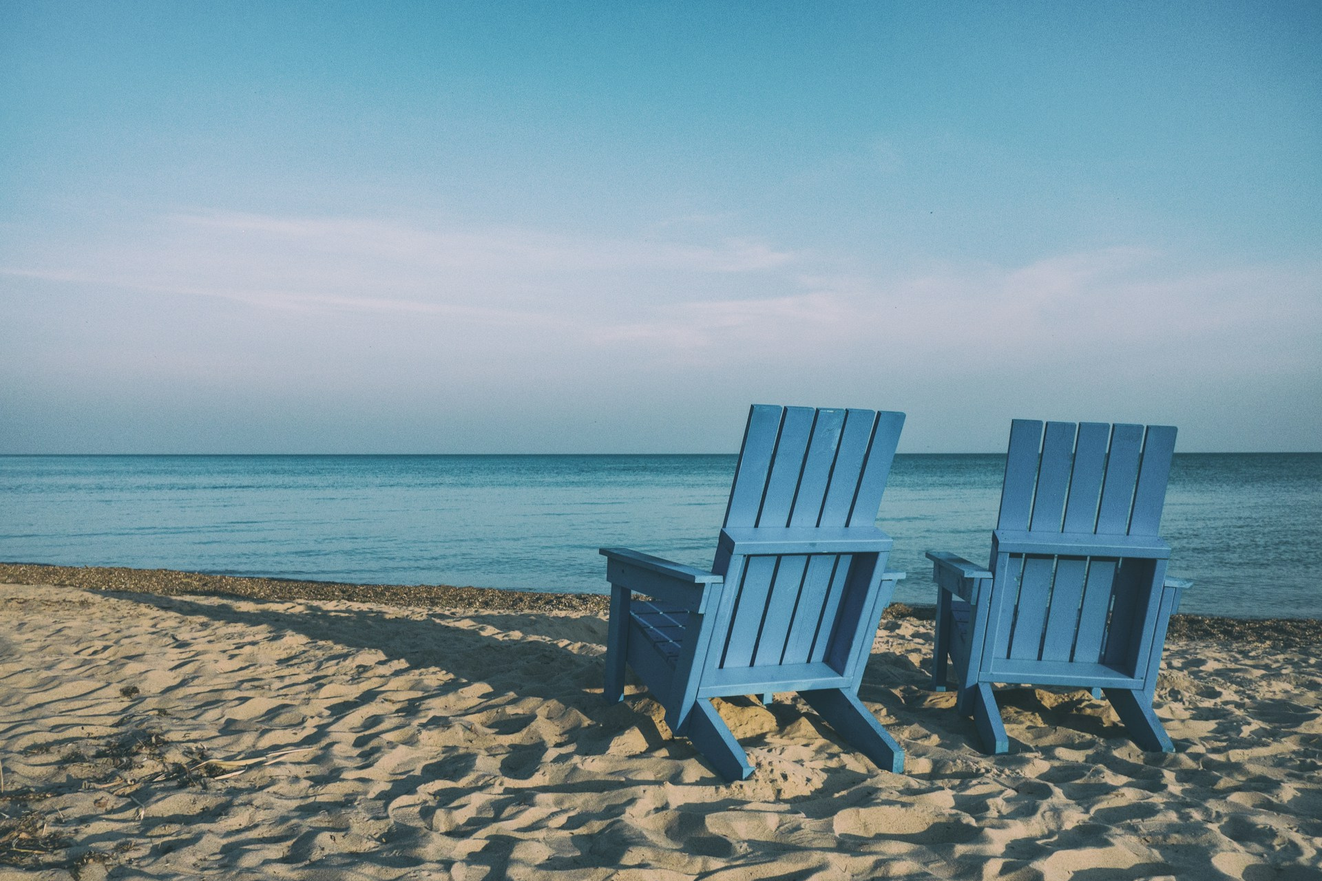 This photograph shows two empty blue chairs on a beach. It’s a stock image so the individuals should not be identified. It’s being used to illustrate that the article it represents is about Why Business Owners Struggle With Retirement. The text alternative is “Why Do Business Owners Struggle With Retirement?” as this best describes the intended impression.