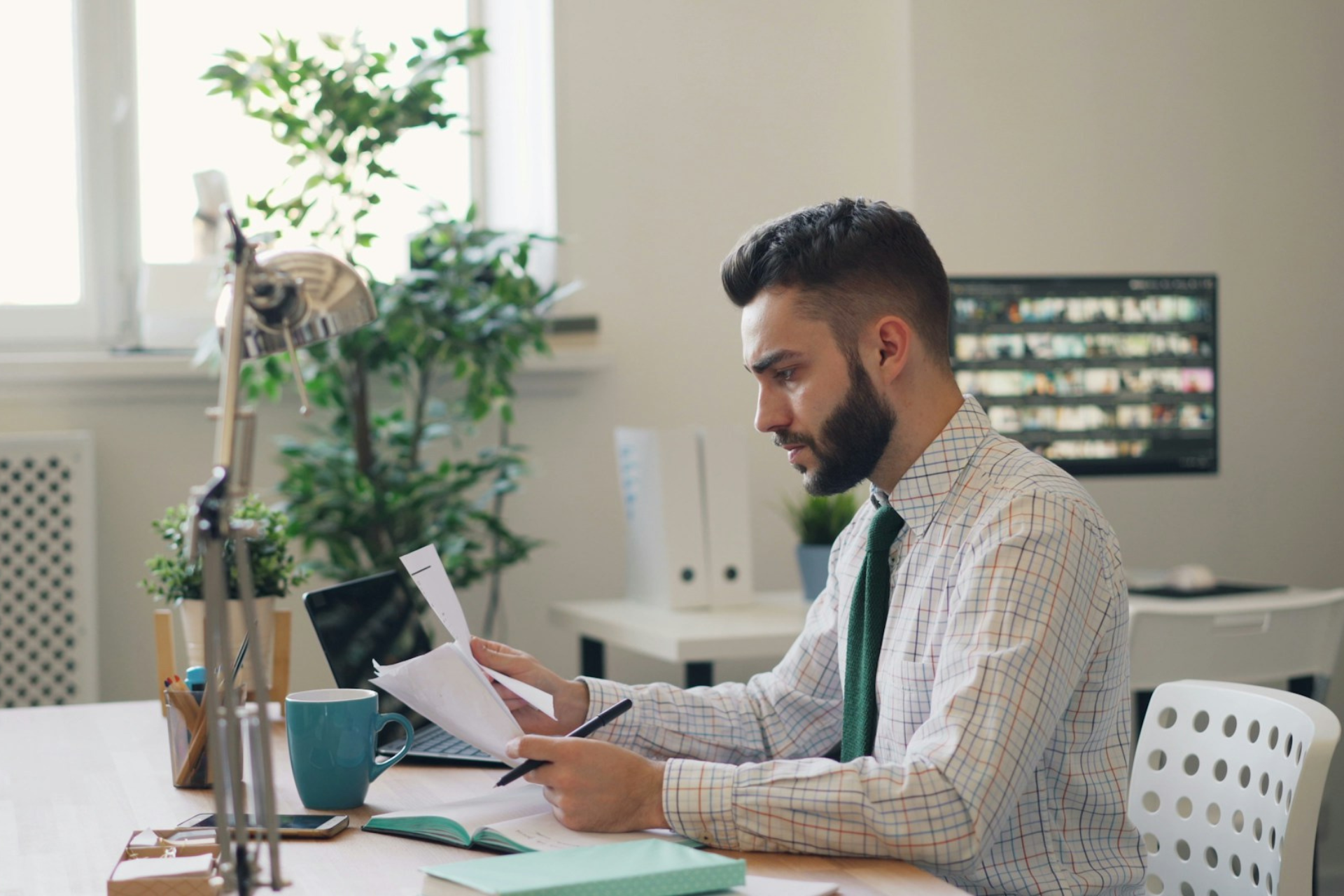 This photograph shows a man at a desk reading documents. It’s a stock image so the individuals should not be identified. It’s being used to illustrate that the article it represents is about The Right Way to Decline a Buyer's Offer. The text alternative is “The Right Way to Decline a Buyer’s Offer” as this best describes the intended impression.